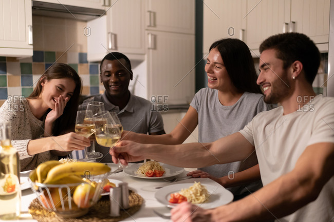 Multiethnic friends clinking wineglasses during dinner