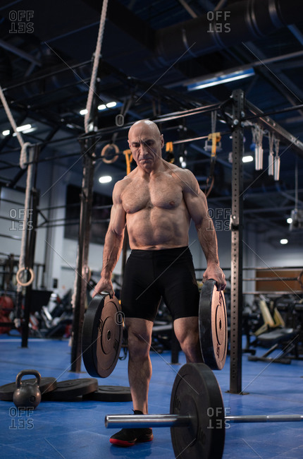 Strong elderly athlete with barbell weight plates