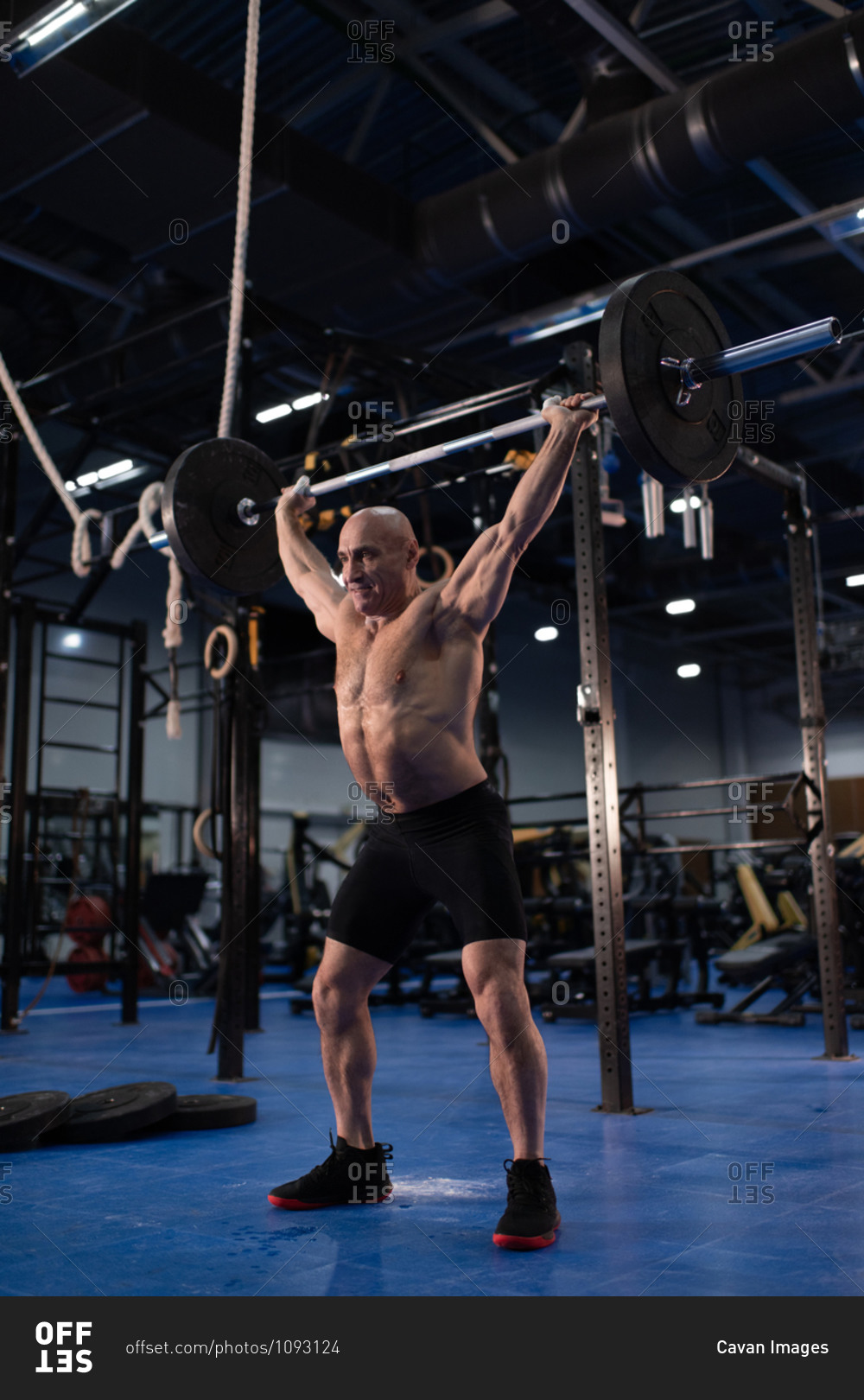 Elderly athlete doing snatch exercise in gym