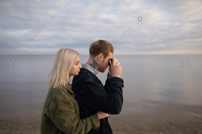 Young couple taking pictures of water in nature