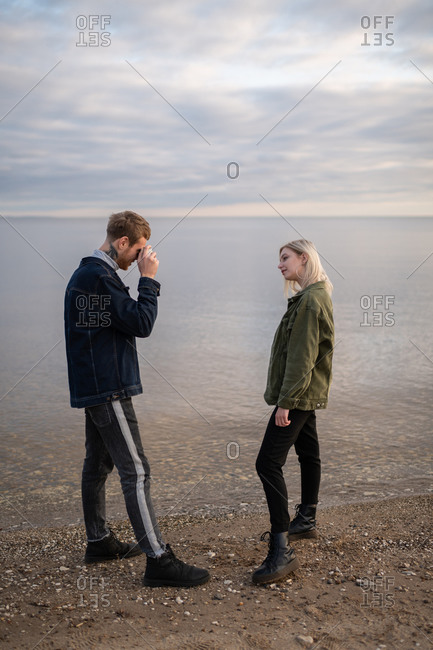 Man taking photos of girlfriend on lake shore