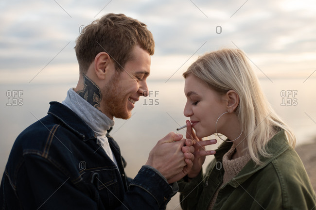 Happy couple smoking weed in evening countryside