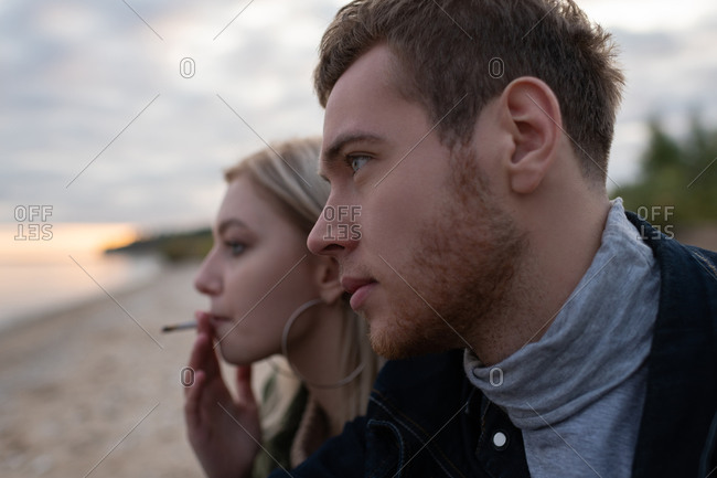 Young hipsters smoking cannabis on empty cold seashore