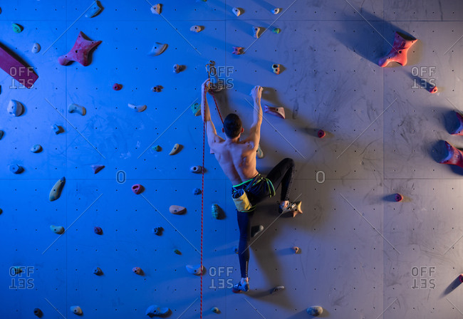 Unrecognizable boulderer with belay exercising on wall
