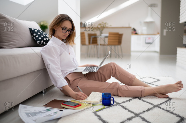 Young woman sitting on turquoise couch on terrace using laptop