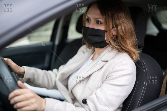 Woman in protective mask driving car