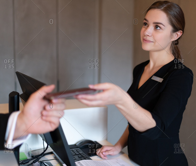 Female receptionist giving room key to businessman after arriving in hotel