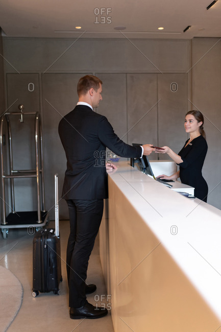 Businessman passing key to receptionist for checkout in hotel
