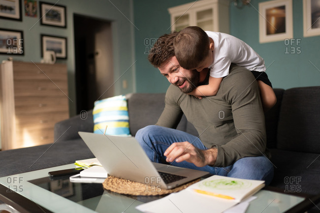 Man working remotely and playing with son at home