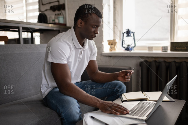 Black man making online order on couch
