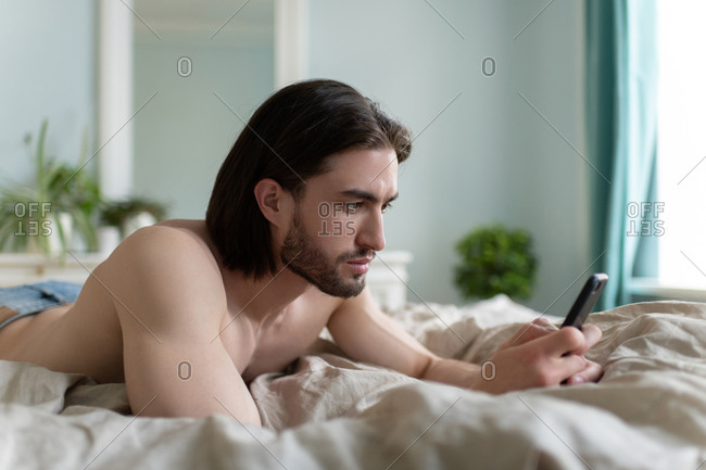 Man using his phone while he lying on bed
