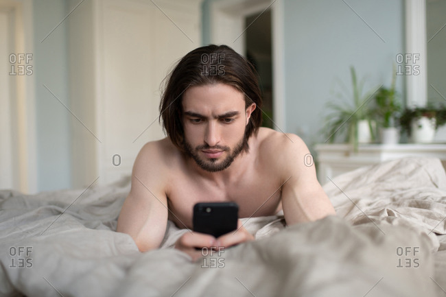 Man using his phone while he lying on bed