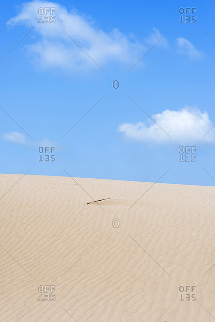 Sand dune under a blue and cloudy sky