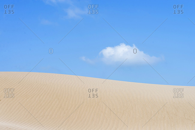Sand dune under a blue and cloudy sky