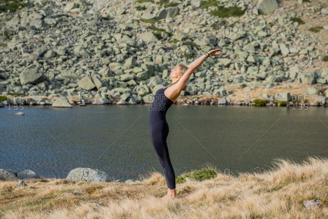 Woman in yoga pose on mountain peak stock photo - OFFSET