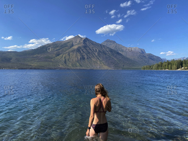 A woman wades into lake mcdonald in glacier national park, mt.