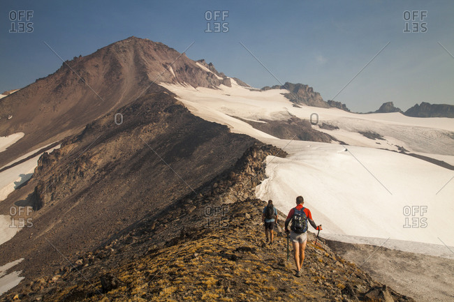 Two hikers climb towards the summit of glacier peak in Washington.