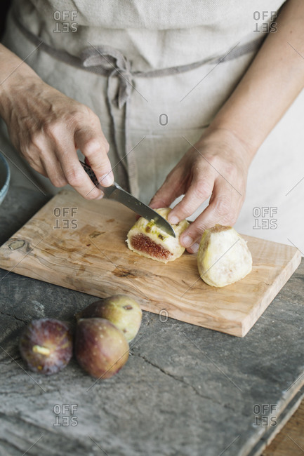 Woman cutting fresh figs on cutting board