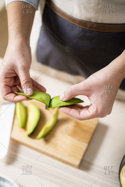 Hands of woman peeling avocados