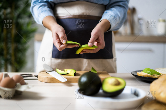 Mid section of woman peeling avocados