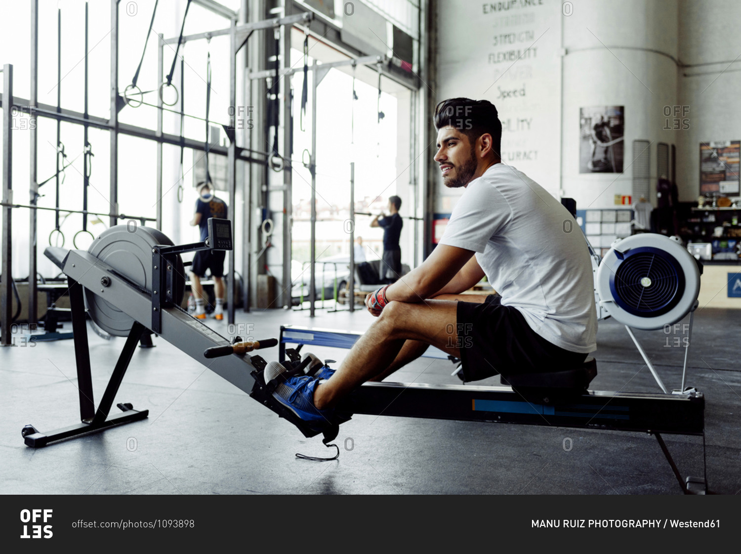 Sportsman looking away while sitting on rowing machine