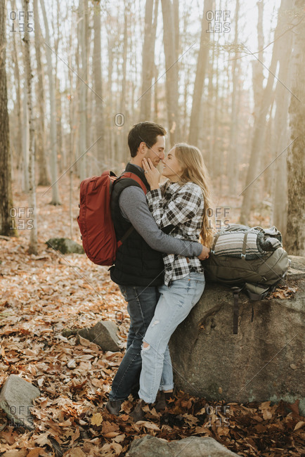 Young couple embracing in front of forest boulder