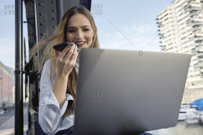 Smiling businesswoman talking on mobile phone while sitting outdoors