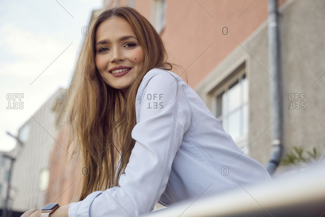 Young businesswoman leaning on railing while standing in balcony