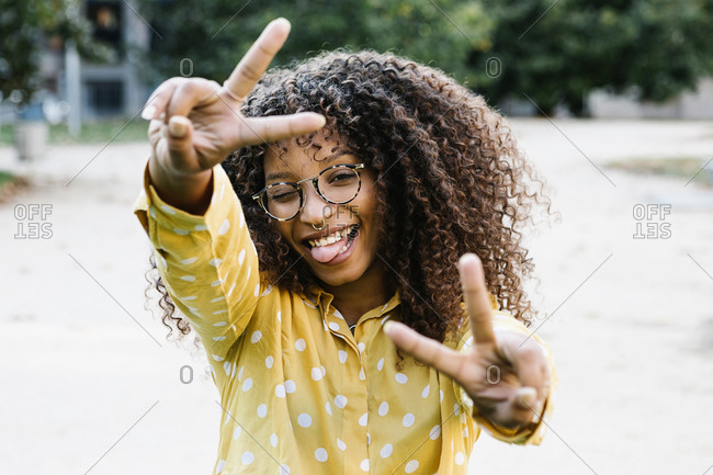 Carefree woman showing peace gesture while standing on footpath