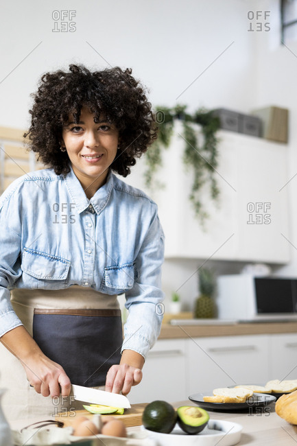 Portrait of young woman preparing vegan sandwiches in kitchen