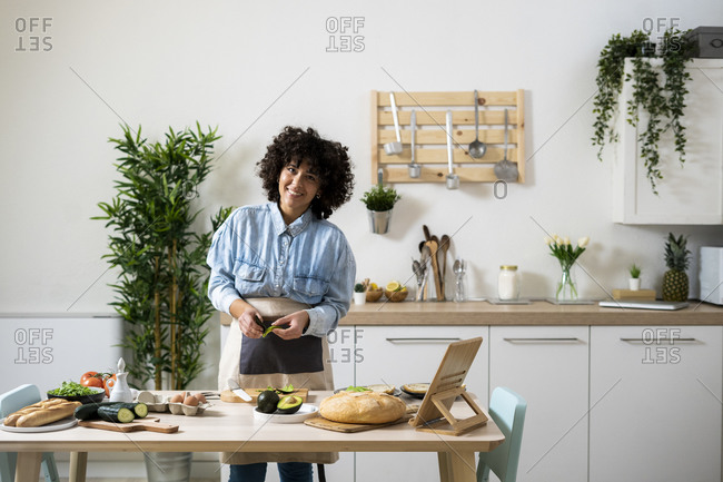Portrait of young woman preparing vegan sandwiches in kitchen