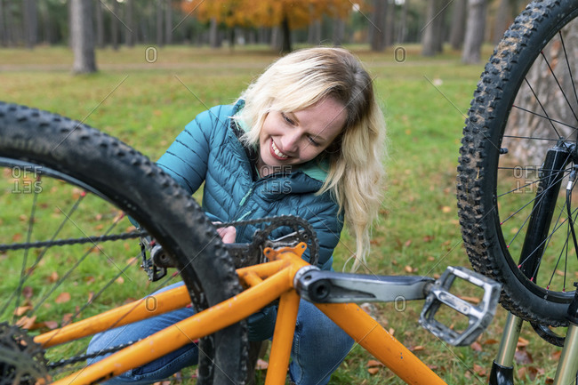 Smiling woman fixing bicycle for riding at Cannock Chase
