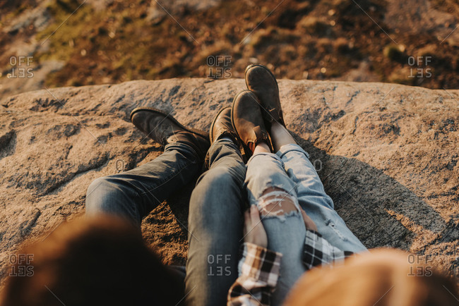 Legs of young couple sitting together on rocky surface