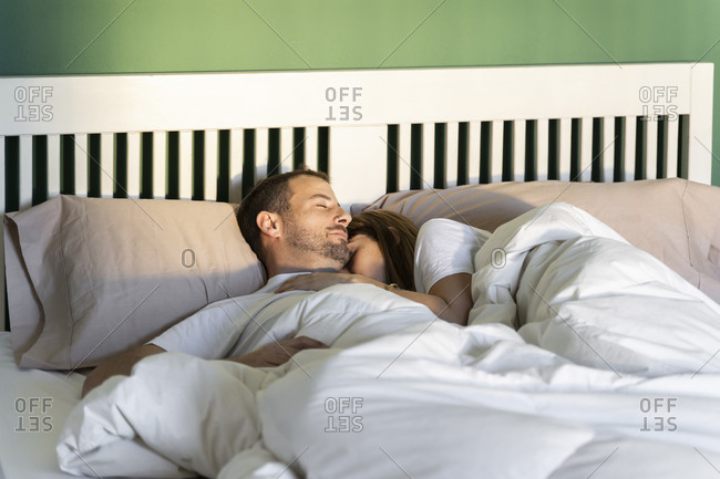 Woman embracing man while sleeping on bed at home