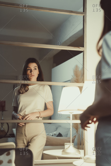 Woman looking at her reflection in mirror at home