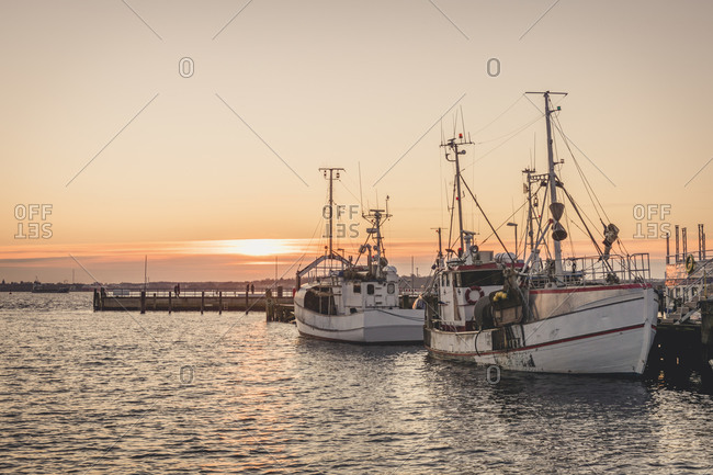 Germany- Schleswig-Holstein- Heikendorf- Fishing boats moored in harbor at sunset