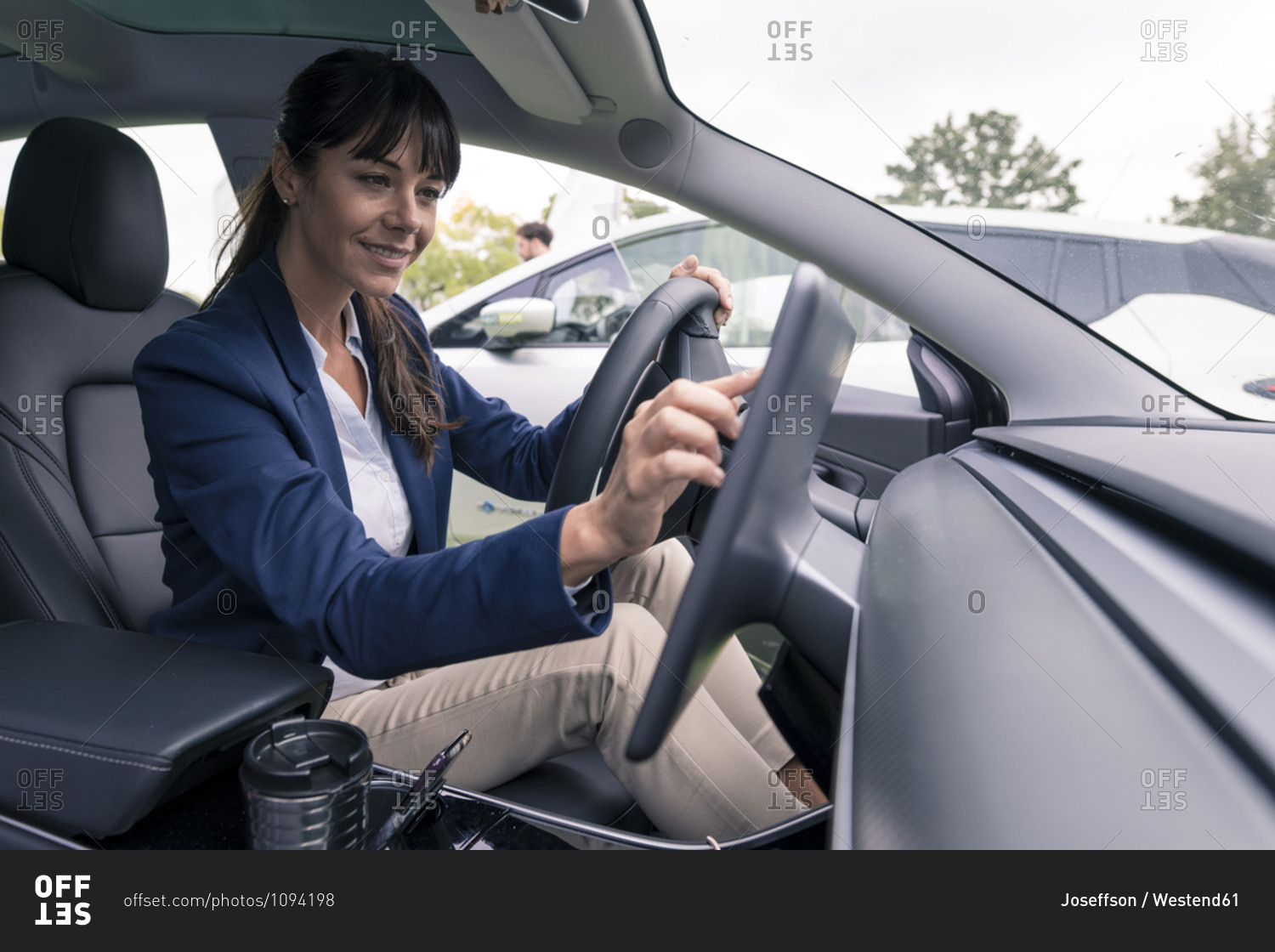 Smiling female entrepreneur navigating through device while sitting in car