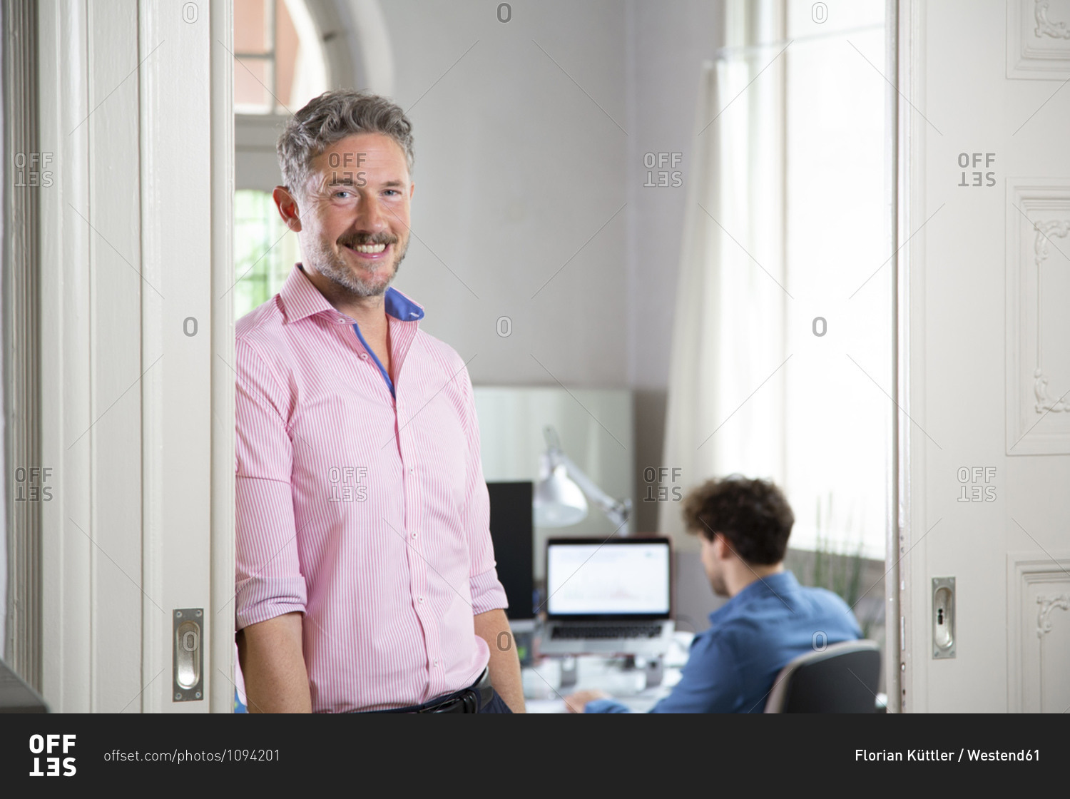 Smiling businessman with  male colleague in background at office cabin