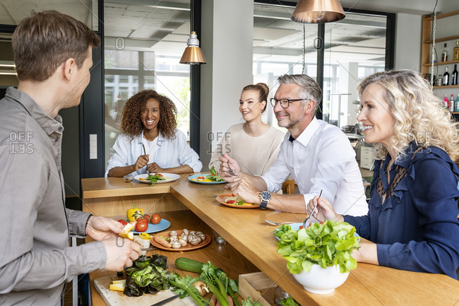 Smiling business people having food on kitchen counter in office
