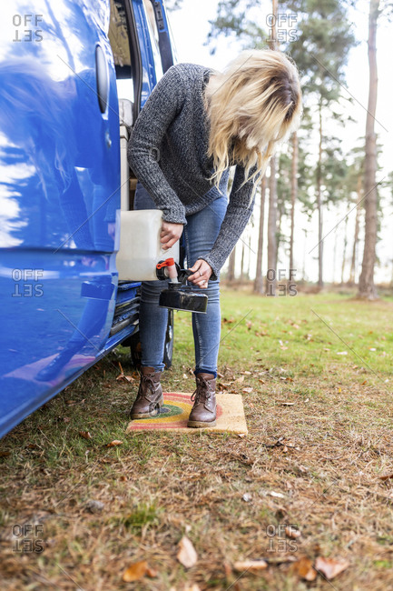 Blond woman filling water in camping teapot at Cannock Chase