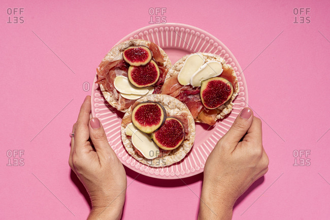 Hands of woman picking up plate with fresh rice cakes