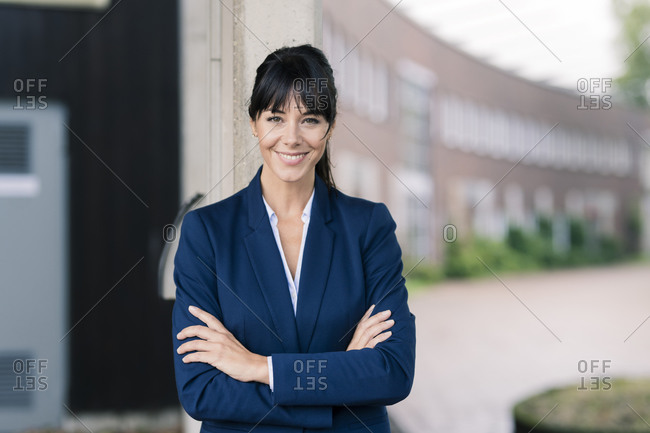 Female professional with arms crossed standing in office park against building
