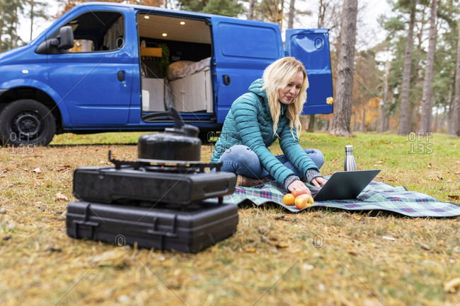 Smiling woman working on laptop while camping in forest at Cannock Chase