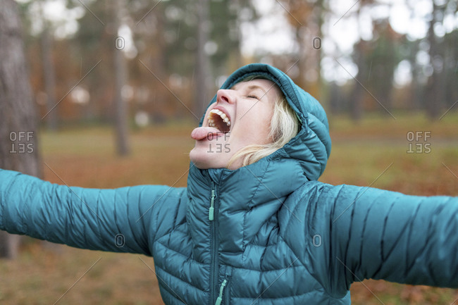 Cheerful woman sticking out tongue while getting wet in rain at Cannock Chase