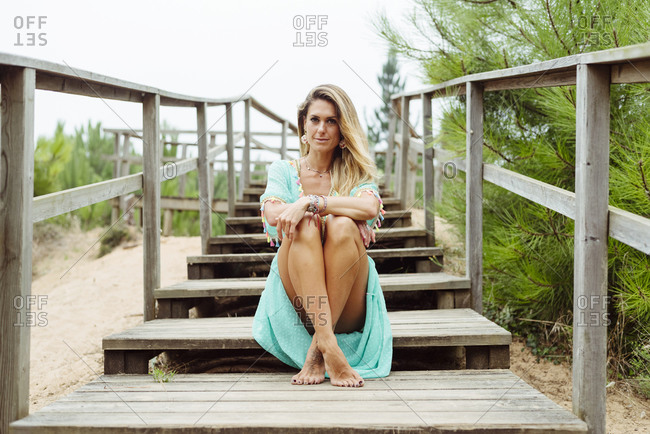 Mid adult woman sitting with legs crossed at ankle on steps at forest