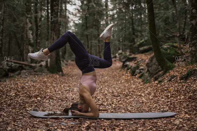 Sports woman practicing headstand yoga pose in forest at Ordesa National Park- Huesca- Spain