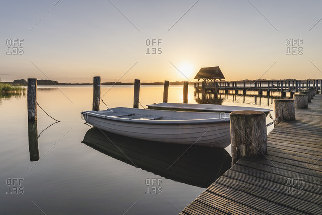 Germany- Schleswig-Holstein- Hemmelsdorf- Rowboats moored to pier on shore of Hemmelsdorfer See lake at sunrise