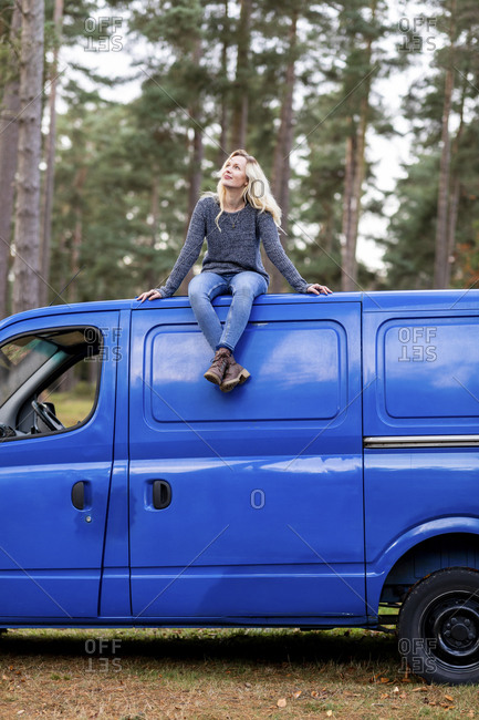 Woman with blond hair looking up while sitting on top of motor home at Cannock Chase