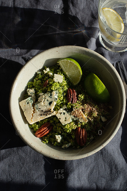 From above bowl with broccoli salad with couscous placed on dark fabric napkin