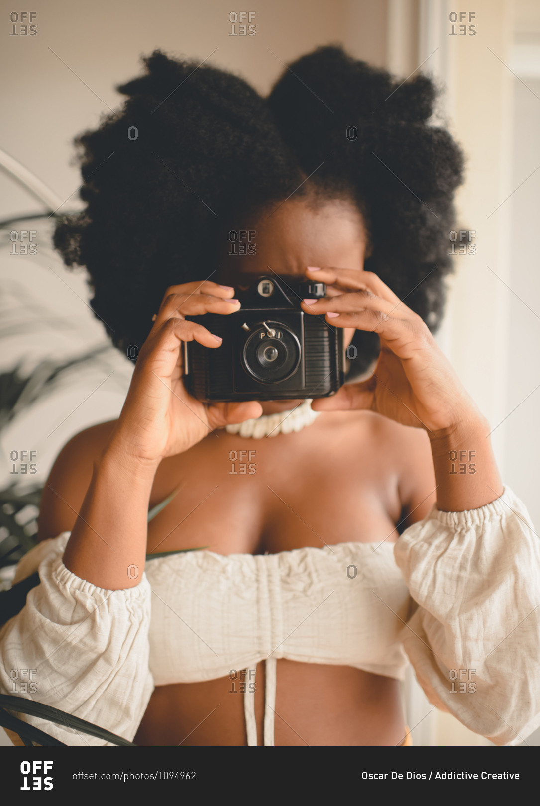 Unrecognizable African American female photographer taking shots with vintage instant photo camera